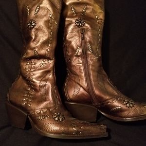 Copper looking leather  boots with strips of decor on them